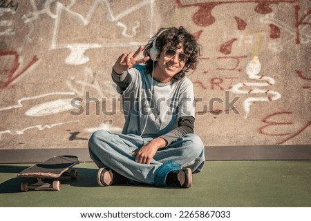 boy with skateboard and headphones doing the peace gesture