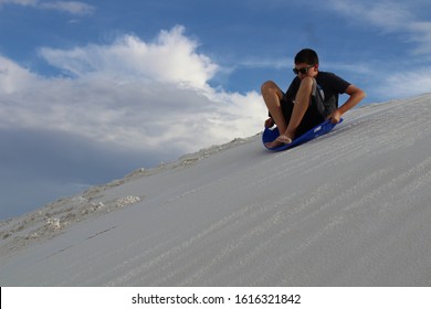 Boy Sledding Down A Sand Dune