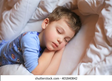 Boy Sleeping In Pajamas On White Bed