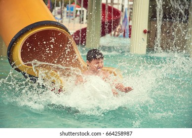 Boy Sliding Down Slide In Waterpark.