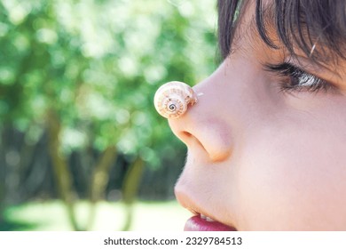 Boy with snail on his nose as a pet