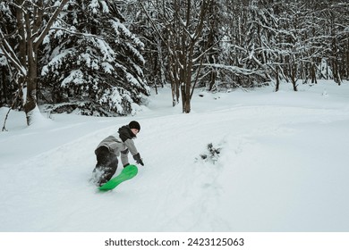 A boy snowboards in a winter snowy forest and falls - Powered by Shutterstock