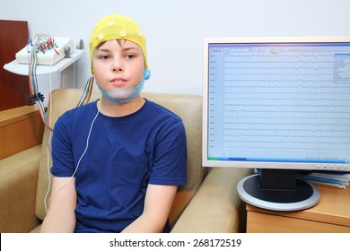 Boy in a special cap during electroencephalography next to the monitor with readings