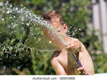 Boy Squirting Water From A Hose