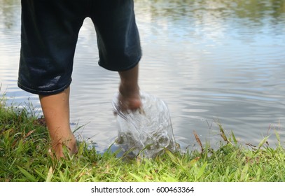 the boy stand alone in front of river and kick water can fall river, It's dangerous cause can drowning.