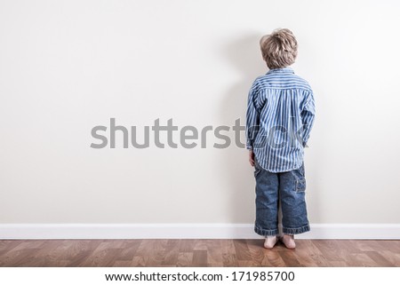Boy standing up against a wall