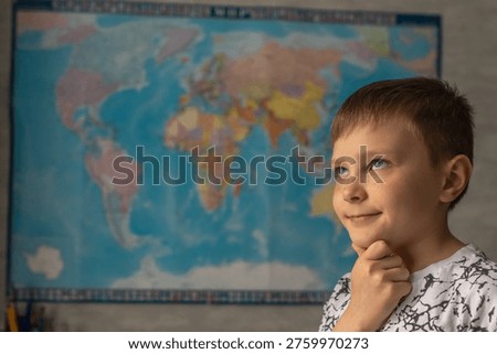 A boy standing in front of a world map. He is thinking about where he would like to go on vacation.