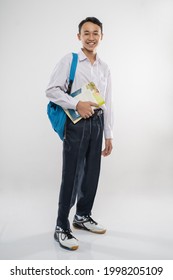 a boy standing in junior high school uniform smiling holding a book and school bag on an isolated background