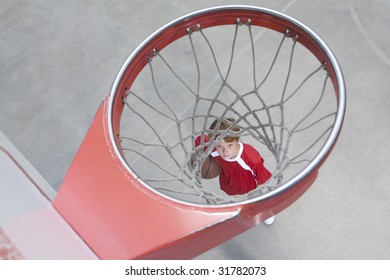 Boy standing looking up through basketball hoop
