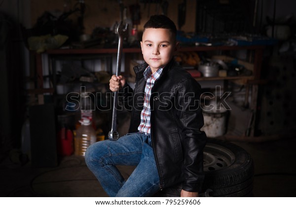 \
boy standing at the mechanic with tools in the\
garage