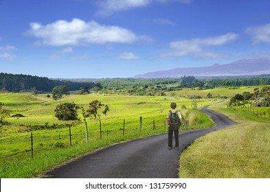 A Boy Standing On A Long And Winding Country Road.