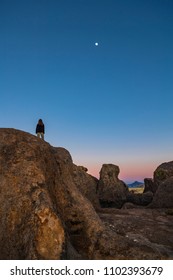 Boy Standing On Top Of A Big Boulder Looking Up To The Stars And Night Sky