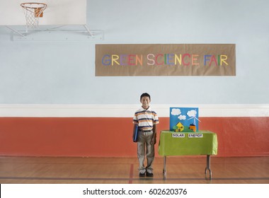 A Boy Standing Under A Green Science Fair Sign Beside A Solar Power Presentation,