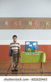 A Boy Standing Under A Green Science Fair Sign Beside A Solar Power Presentation,