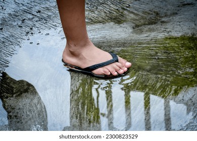 A boy stands in a puddle of rainwater on an alleyway. - Powered by Shutterstock