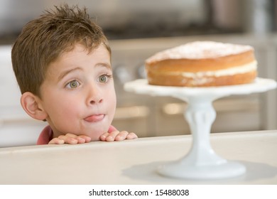 Boy Staring Longingly At Cake At Home Licking Lips