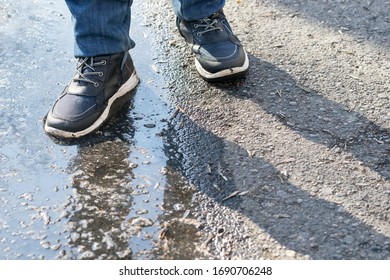 The boy stepped into a puddle on the road. A muddy puddle on the asphalt.