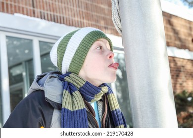 Boy sticking his tongue to a flag pole