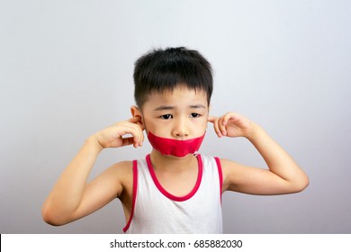 Boy Sticks Finger In Ears With Red Tape Over Mouth