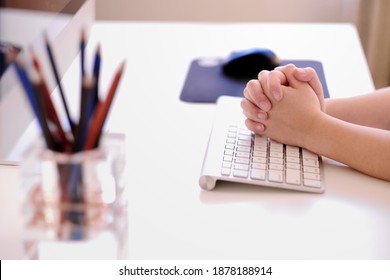 Boy Student Holding Hands With His Fingers Interlaced On The Computer Keyboard And Listening Online Teaching Course At Home During Covid-19 Pandemic. Remote Learning Through Online Classroom Concept.