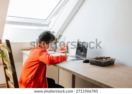 Boy student learning online using laptop at home