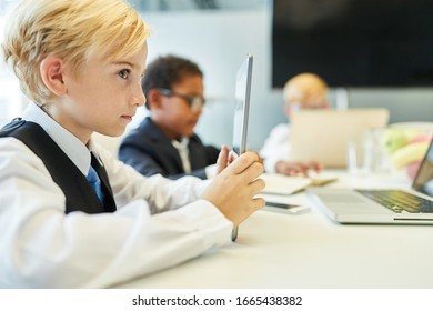 Boy as a student using tablet computer in a class or business meeting