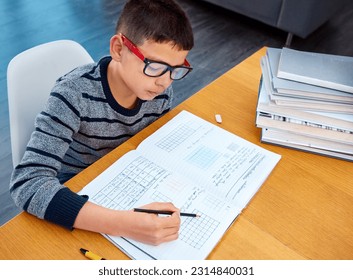 Boy, student and writing in book for math, studying or homework for learning, assessment or education on table. Smart kid, young child and busy reading mathematics textbook, problem solving and focus - Powered by Shutterstock