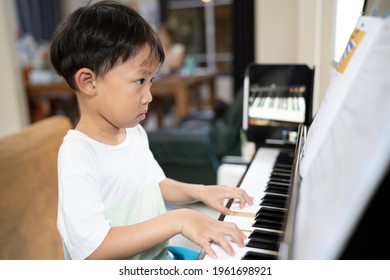 A boy is studying piano online with tablet in house.