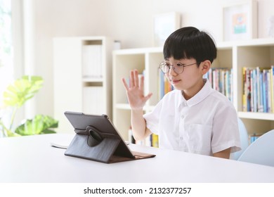 Boy studying via internet online with laptop and tablet, greeting teacher and friends, taking network video lessons at home
 - Powered by Shutterstock