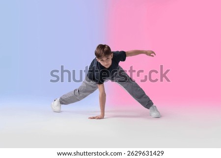 Boy in stylish clothes dancing on color background