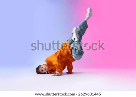 Boy in stylish clothes dancing on color background