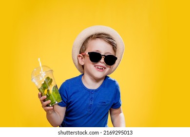 Boy In Summer Outfit Wearing Sunglasses And Enjoying While Drinking A Mojito Cocktail. Posing On The Yellow Background