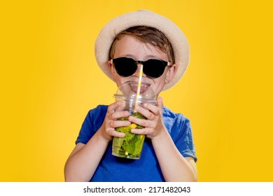 Boy In Summer Outfit Wearing Sunglasses And Enjoying While Drinking A Mojito Cocktail. Posing On The Yellow Background