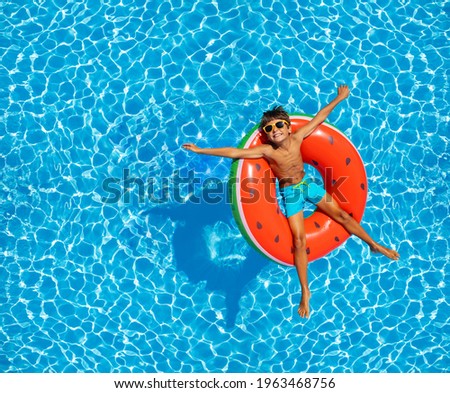 Boy swim in pool on inflatable ring from above