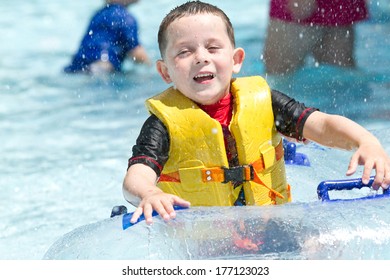 Boy In Swimming Pool Smiling, Wearing A Life Vest