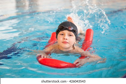 Boy  Swimming With A Red Foam Noodle In A Indoor Pool