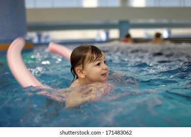 Boy Swimming With Swim Noodle In The Pool