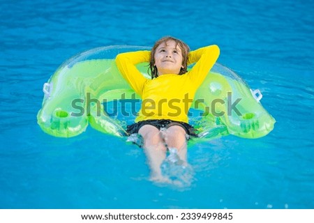 Boy swims in pool with float. Swimming, summer vacation. Child swim in pool on inflatable ring. Kid with inflatable ring in swimming pool. Summer vacation. Child swiming. Kid floating in sea water.
