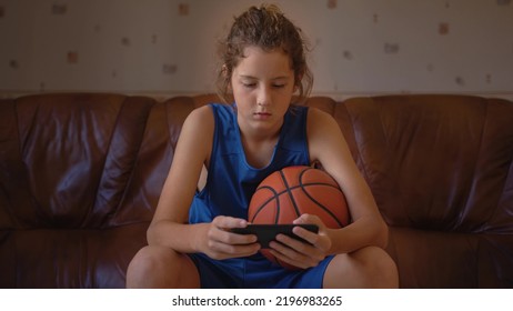 Boy taking break after basketball game and drink fresh water from bottle. Sport concept. Rehydration after basketball game. Basketball player drinking water. Boy in a blue basketball uniform - Powered by Shutterstock