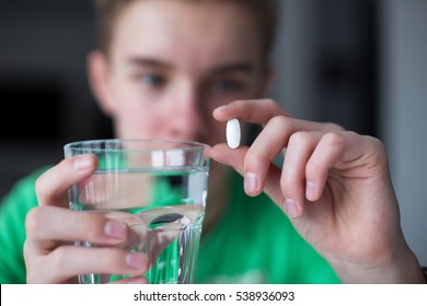 Junge, der Medikamente und ein Glas Wasser einnimmt.