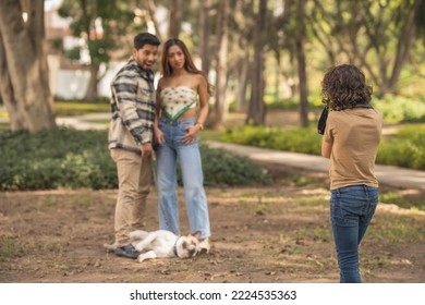 Boy Taking A Photo Of A Couple With A Dog In A Park