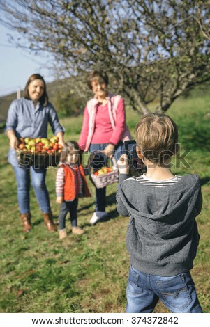 Image, Stock Photo Boy taking photo to family with apples in basket