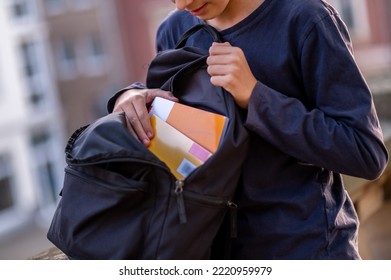 Boy taking textbooks out of the open schoolbag - Shutterstock ID 2220959979