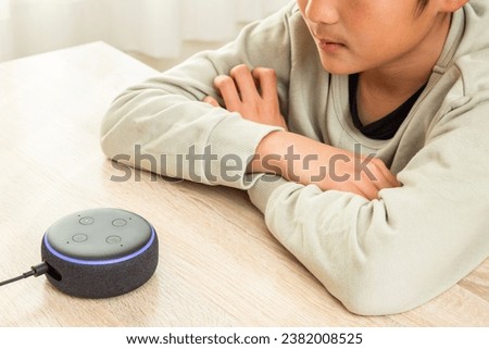 A boy talking to a smart speaker.