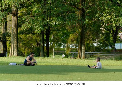 A Boy Is Teaching His Father How To Toss A Frisbee In Bishan Park, Singapore 21 June 2021.    