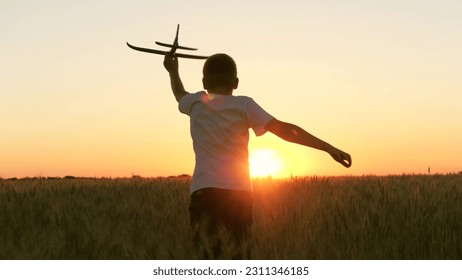 boy teenager child kid runs through field with wheat with toy plane his hands sunset, happy dream family, become pilot, kid wheat plays with toy field, sunset park, spring break, little pilot runs - Powered by Shutterstock