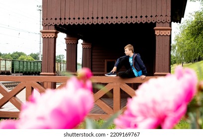 Boy Teenager Sitting On A Wooden Veranda At The Station