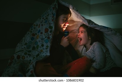 Boy telling a story to his sister lighting up with a flashlight