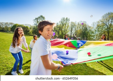 Boy throwing balls up by using rainbow parachute