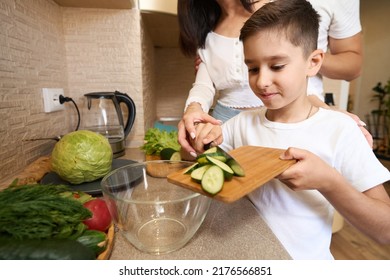 Boy Throwing Cucumber Slices From Cutting Board Into Bowl